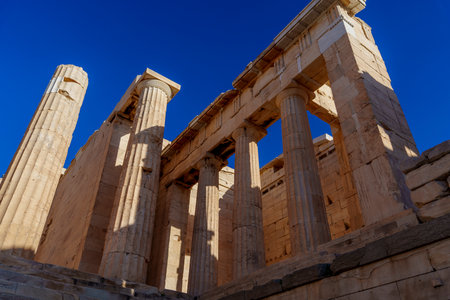 Imposing marble columns and monumental entrance of the Propylaea on the Acropolis in Athens, contrasted against a clear blue sky.の写真素材