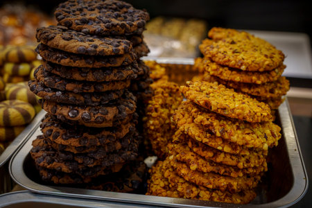 Tall piles of dark chocolate chip cookies and golden nut cookies on a tray.の写真素材