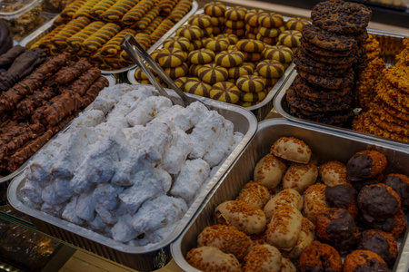 Metal trays filled with powdered, chocolate and nut cookies tempting customers in a busy bakery.の写真素材