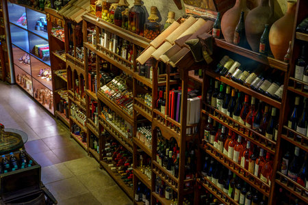 Packed wooden racks display rows of local wine, sauces and crafts beneath decorative tiled mini...