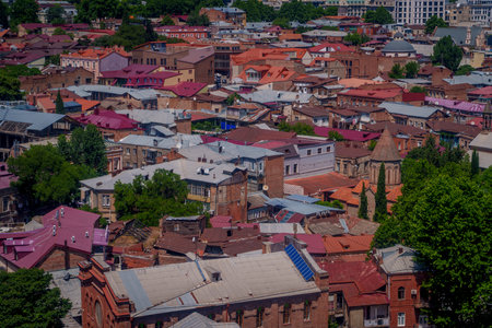 Dense patchwork of colorful metal and tile roofs covers historic brick houses and courtyards in Old Tbilisi district.の写真素材
