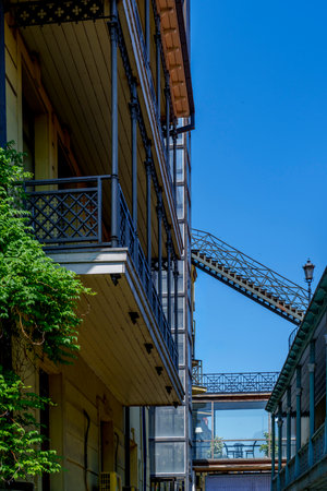 Traditional wooden balconies line a tight passage while an external metal staircase and skybridge cross overhead.の写真素材