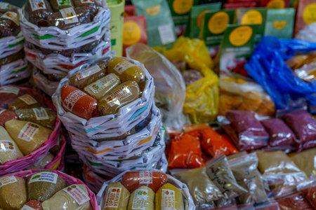 Baskets and bags filled with various colorful spices arranged on a busy market stallの写真素材