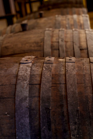 Close-up view of worn wine barrels shows aged wooden staves bound by rusted metal bandsの写真素材