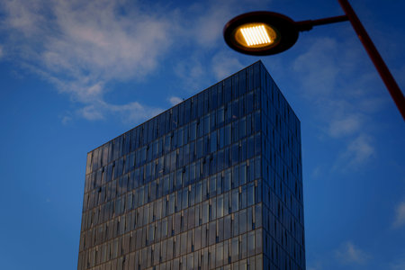 Reykjavik, Iceland - January 28, 2026: Streetlight frames a modern glass office tower at dusk.
