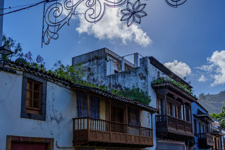 Old town facades with carved timber balconies sit beneath festive street lights and clouds.の写真素材