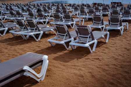 Deserted resort beach with many sunbeds on sand, ready for tourists and relaxation.の写真素材