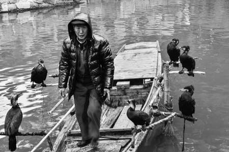 Fisherman on cormorant fishing boat floating on a Tongli river in China.のeditorial素材