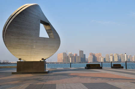 Modern art, sculpture, built next to a water with city skyline on horizon.のeditorial素材