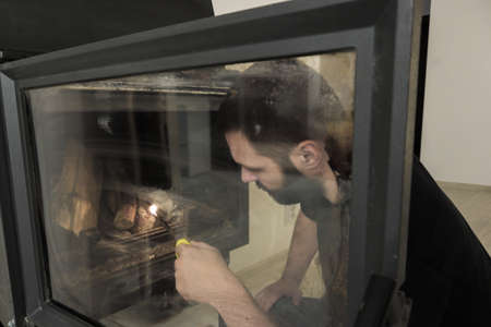 Closeup of young caucasian man starting a fire in fireplace.