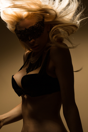 Beautiful, sexy blond woman in black underwear and maskの写真素材