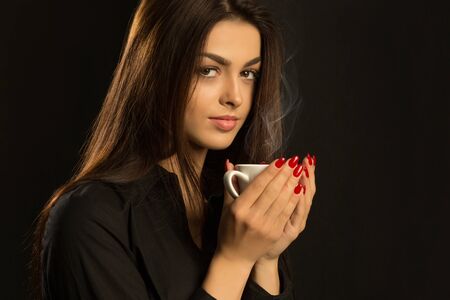 Sexy sensual woman in black blouse drinkig coffeeの写真素材
