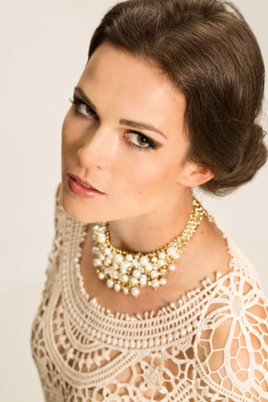 Young woman with pinned hair and jewellery standing over gray backgroundの写真素材