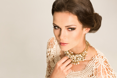 Young woman with pinned hair and jewellery standing over gray backgroundの写真素材