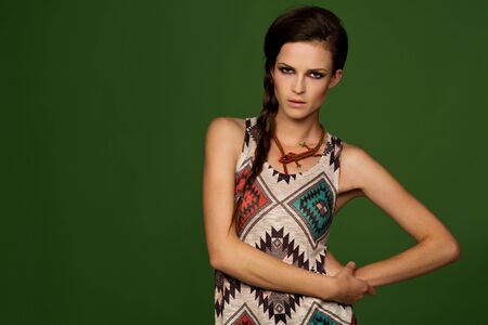 Young beautiful girl with smoky eyes stansing among dark green backgroundの写真素材