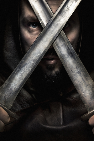 Man dressed in barbarian style with sword and moustache, bearded screaming ready to fightの写真素材