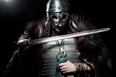 Screaming viking warrior with sword, armour and helmet over black backgroundの写真素材