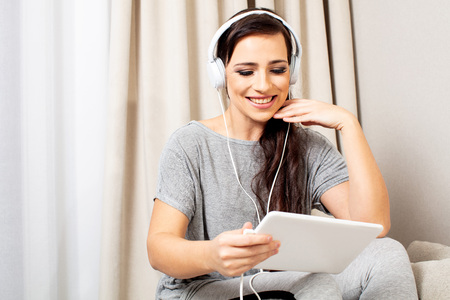 Portrait of a smiling pretty woman posing with headphones and tabletの写真素材