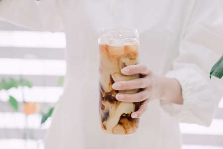 Woman's hand pouring milk to make caffe latteの写真素材