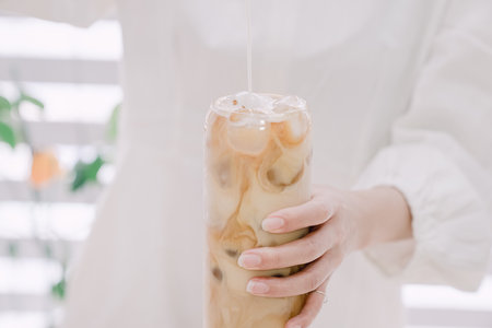 Woman's hand pouring milk to make caffe latteの写真素材