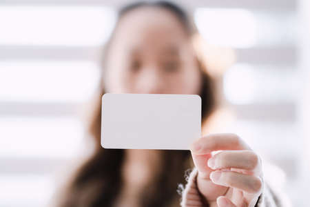 woman with arms outstretched and holding a business cardの写真素材