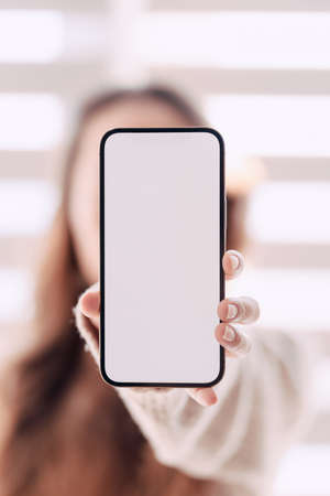 Woman with arms outstretched and holding out her phoneの写真素材