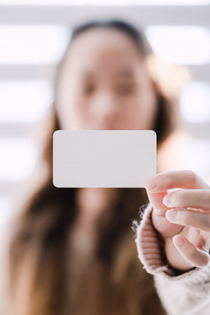 woman with arms outstretched and holding a business cardの写真素材