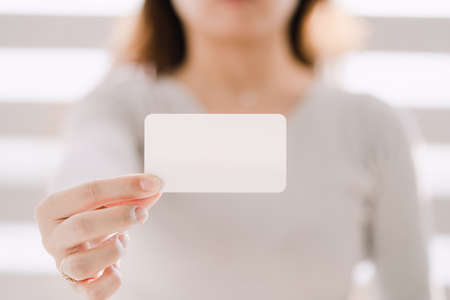 Woman with arms outstretched and showing business cardの写真素材