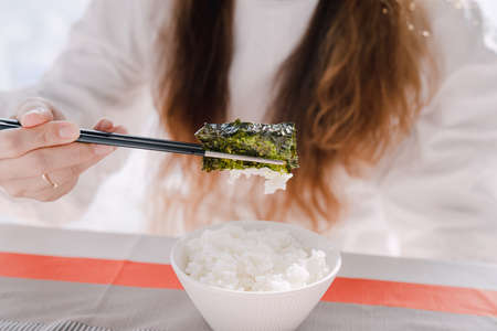 Woman holding rice and Korean seaweed with chopsticksの写真素材