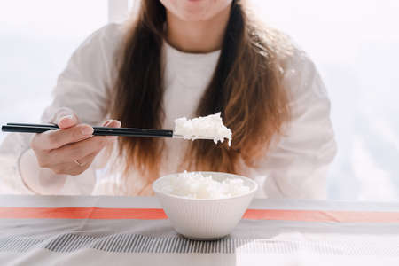 Woman holding white rice with chopsticksの写真素材