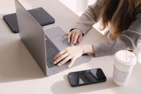 Hands working with laptop at office desk with coffee and mobile phoneの写真素材