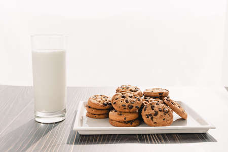 A lot of chocolate chip cookies and milk stacked
