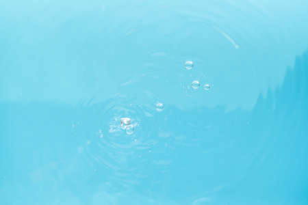 water drops falling on blue waterの写真素材