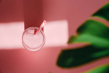 Glass of tasty cocktail with straw on pink background, flat lay. Space for textの写真素材