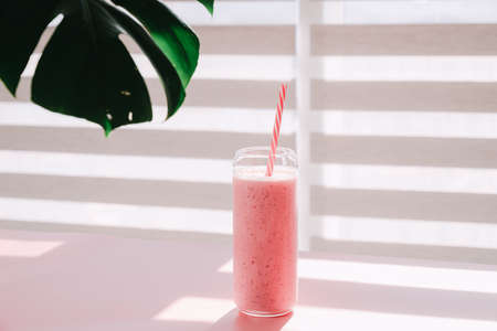 Strawberry smoothie in a glass with a straw on a white background.の写真素材