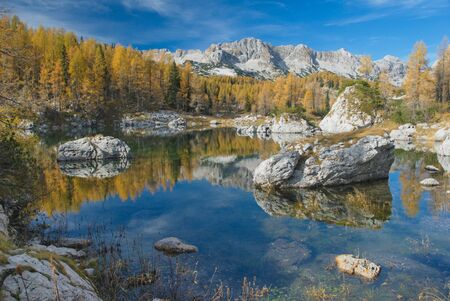 Mt Lepo spicje reflections in Double lake, with fall color of the larches around the lakeの写真素材