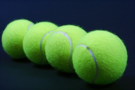 four tennis ball on dark backgroundの写真素材