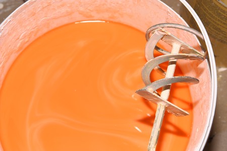 Mixing orange paint in bucketの写真素材