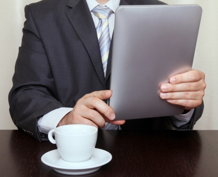 Businessman reading news on tablet and drinking coffeeの写真素材