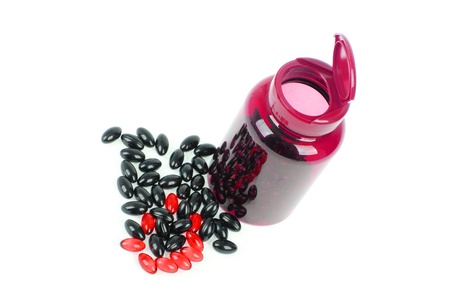 Red and black pills spilled around a pill bottleの写真素材