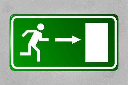 Emergency exit sign hanging on a concrete wallの写真素材