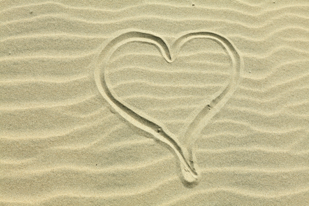 Heart drawn in the sand. Beach background. Top viewの写真素材