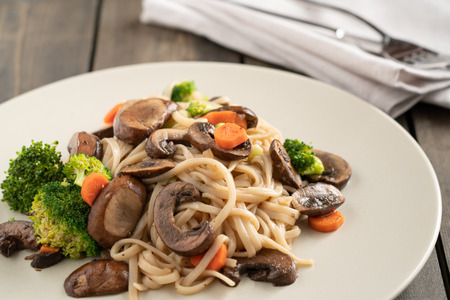 Mushroom stir-fry served on white plate and wood tableの写真素材