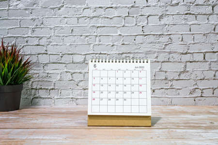 June 2022 white calendar with potted plant on wooden desk. Celebration and event concept. Copy space.の写真素材
