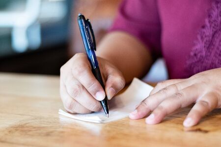 The hand of a female holding a pen to write notes on a notebookの写真素材