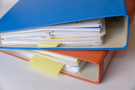 A orange and a blue binder isolated with documents.の写真素材