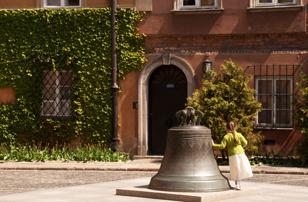 Poland.Warsaw Old town. Bell in the Kanonia Square,legend said if you circle it 3 times will bring you good lucks. girl goes around the bell.Photo was taken in May 2007の写真素材