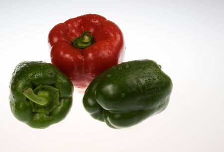 Three coloured peppers with drops of water on the isolated white background.One red pepper and two green peppers.Red pepper in the middle and two green on the sides.Horizontal view.の写真素材