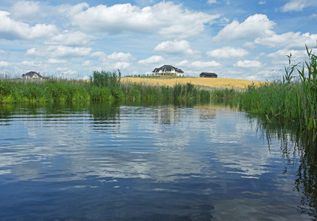 Poland in summer.Pomerania.Horizontal view on the Brda river.Clouds beautifully reflected in the water and in the distance you can see the houses.Nature landscape.の写真素材
