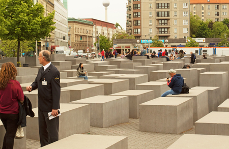 Germany-Berlin, May 2016. Memorial for the Murdered Jews of Europe.Guide Provides tourism information and people sitting on the stone blocks symbolizing the gravestones. Editorial.Horizontal view.のeditorial素材